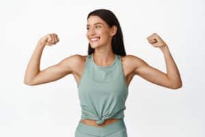 Woman smiling holding up her nicely toned arms from arm lift surgery in Calgary, AB