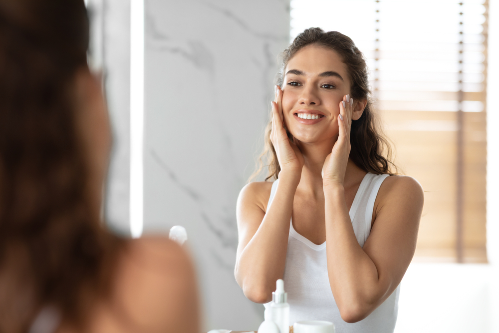 Woman admiring her beautiful skin in the mirror after SkinVive treatment Woman admiring her beautiful skin in the mirror after SkinVive treatment