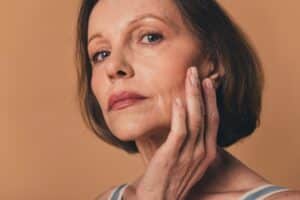 Older woman touching her face after Mohs surgery in Calgary, AB