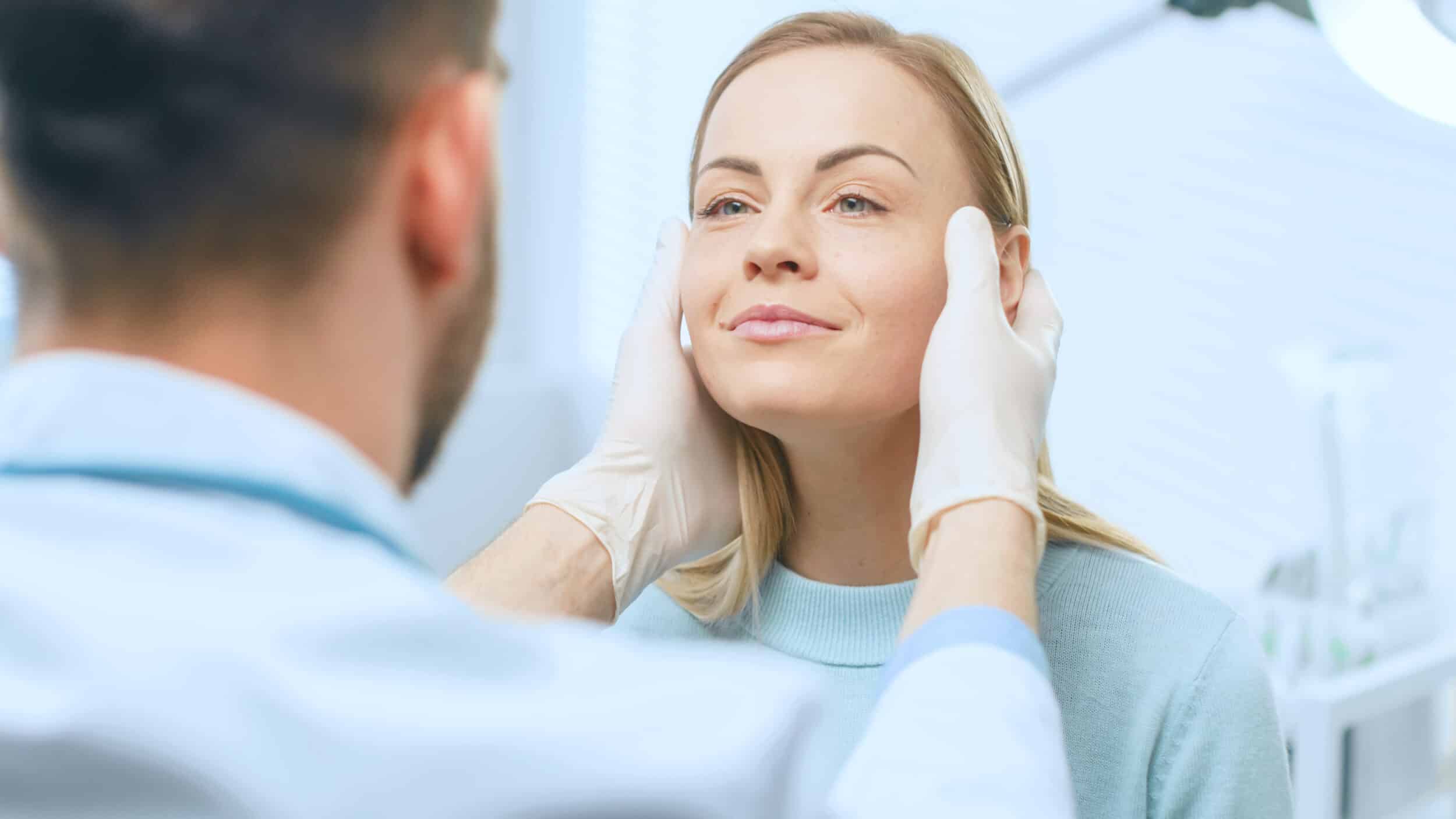 Woman's face being examined by surgeon for a facelift in Calgary, AB