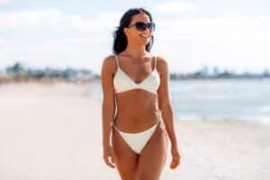 Woman in bikini on beach after breast augmentation in Calgary, AB
