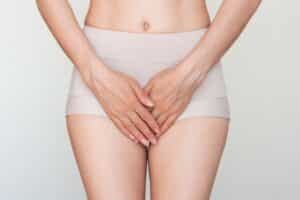 Woman holding lower abdomen due to labial discomfort.